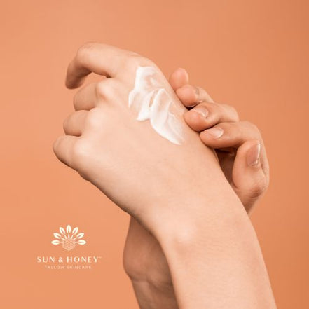 Hand applying tallow sunscreen to another hand with a Sun and Honey Tallow Skincare logo in the corner on a peach background